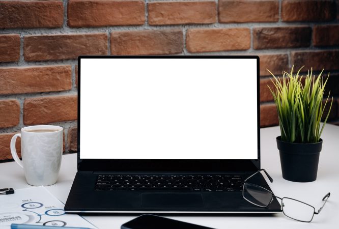 Working desk with blank screen laptop.