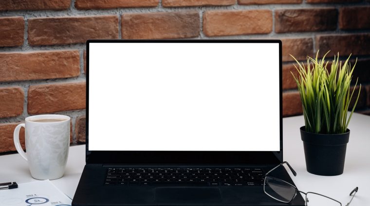 Working desk with blank screen laptop.